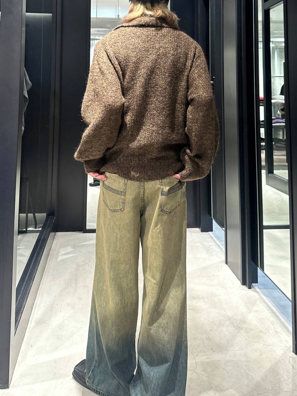 グリーン系のデニムパンツ、イエロー系のニット/セーター、シルバー系のネックレスを着用したメンズの秋コーディネートの4枚目の写真