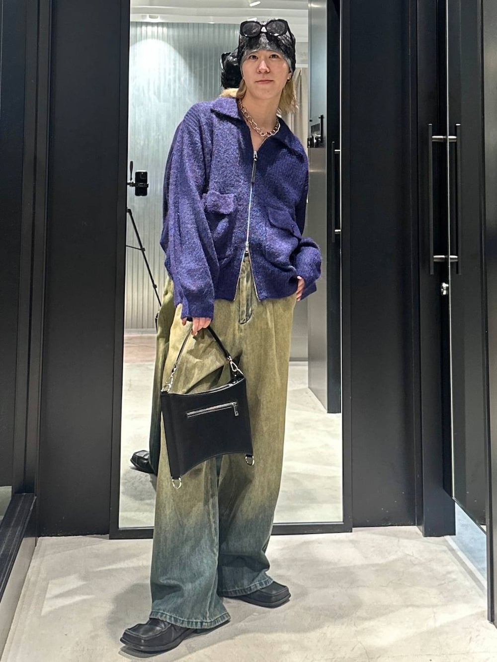 グリーン系のデニムパンツ、ブラック系のショルダーバッグ、ブルー系のニット/セーターを着用したメンズの秋コーディネートの5枚目の写真