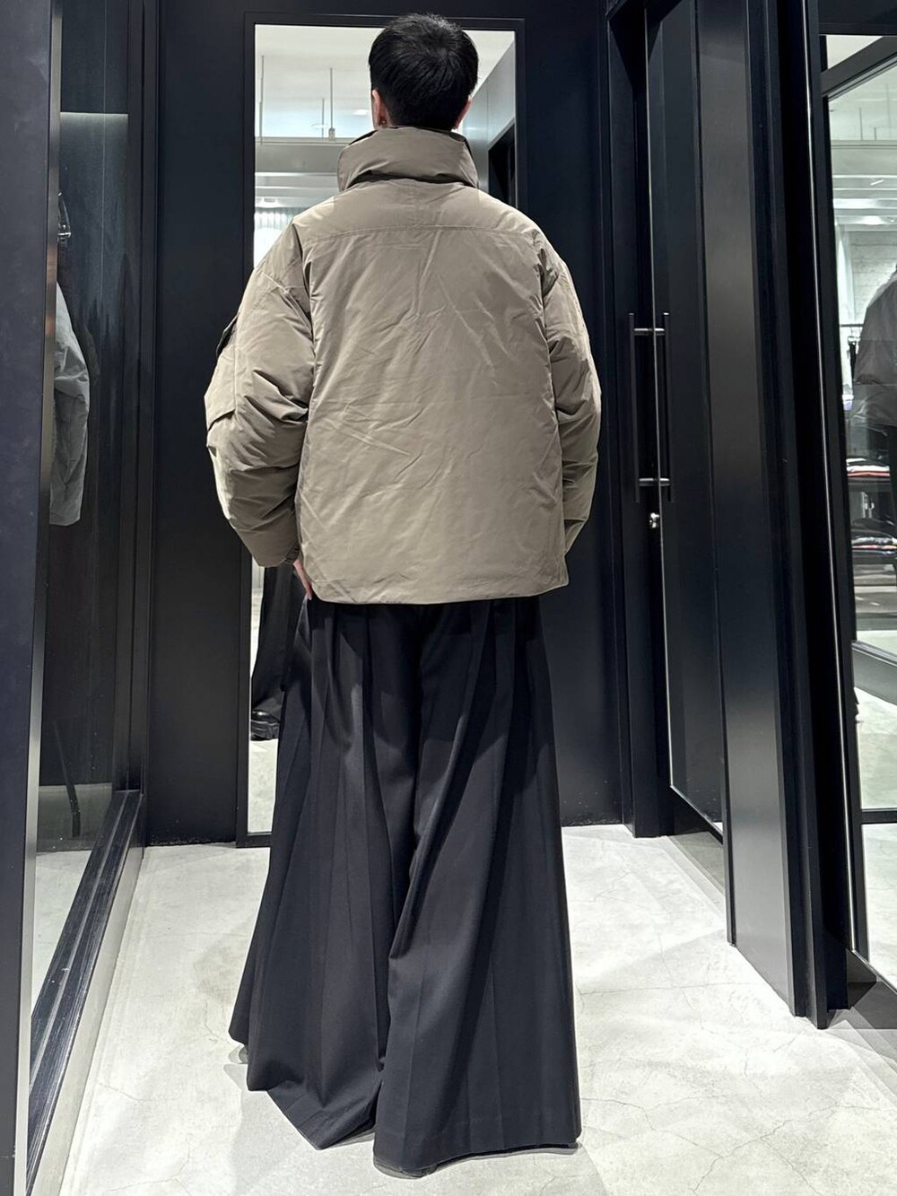 ブラウン系のダウンジャケット/コート、ブラック系のスラックスを着用したメンズの冬コーディネートの2枚目の写真