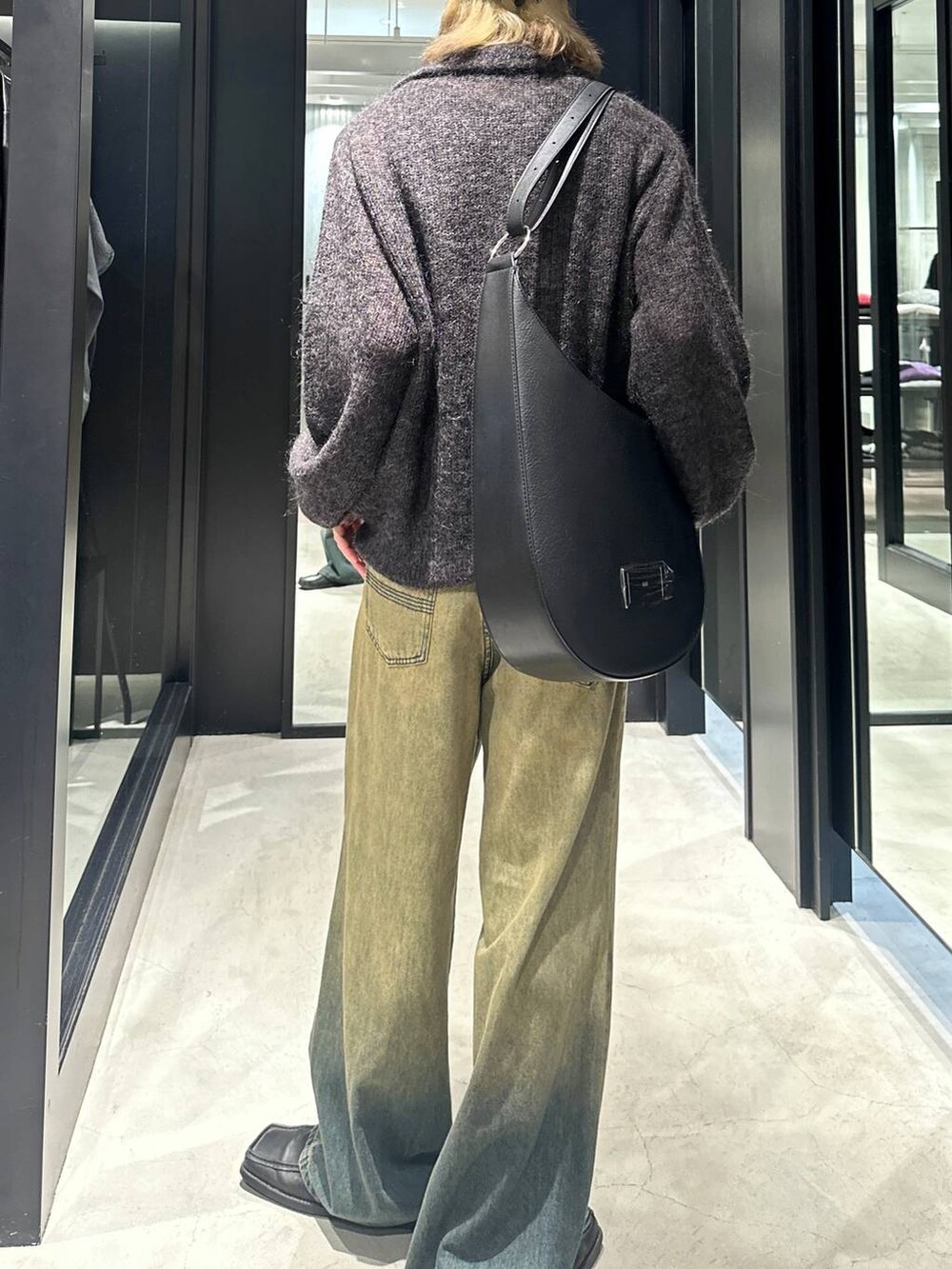 グリーン系のデニムパンツ、ブラック系のニット/セーター、ブラック系のショルダーバッグを着用したメンズの秋コーディネートの4枚目の写真