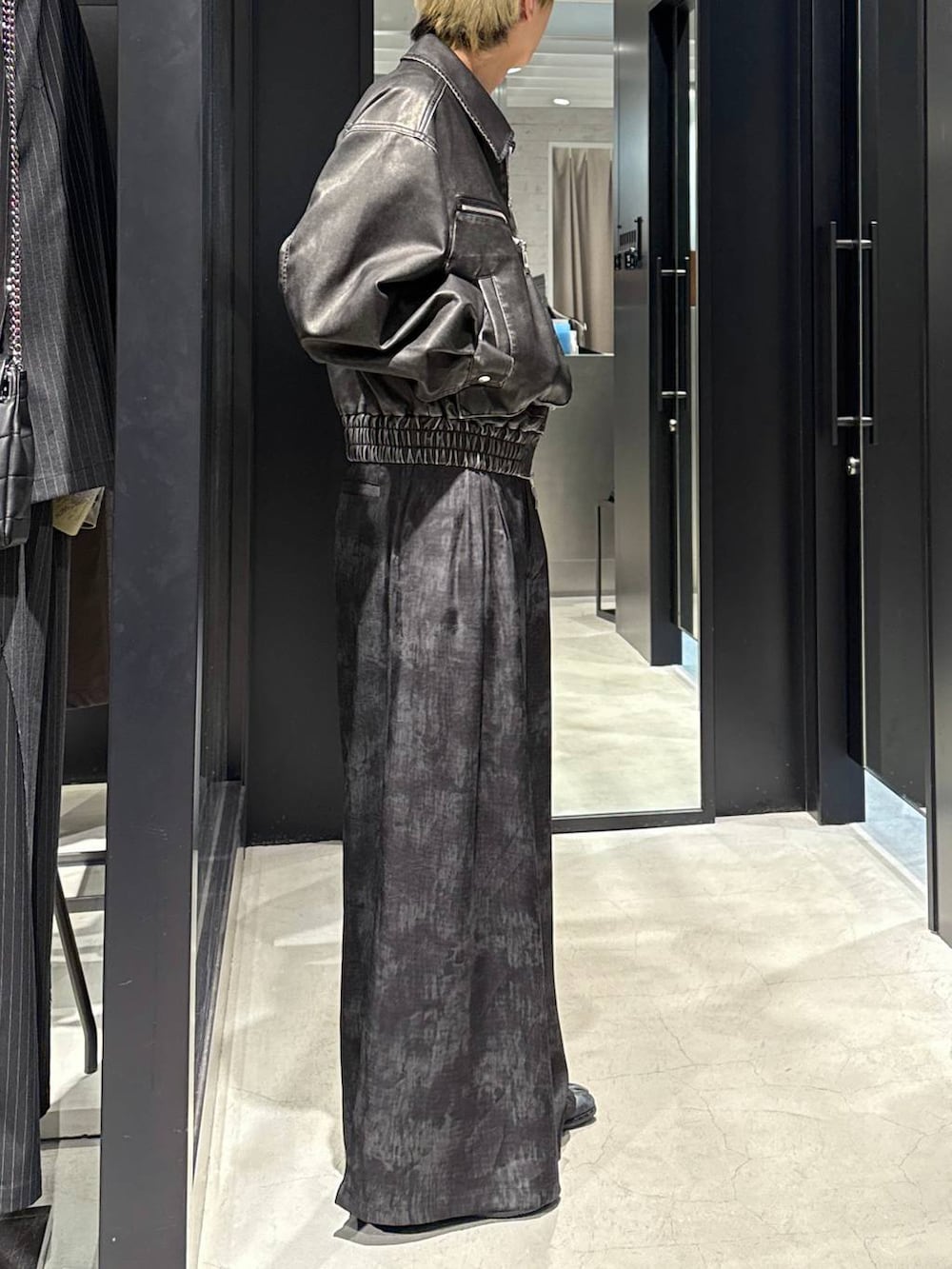 グレー系のスラックス、ブラック系のキャップ、シルバー系のネックレスを着用したメンズの冬コーディネートの2枚目の写真