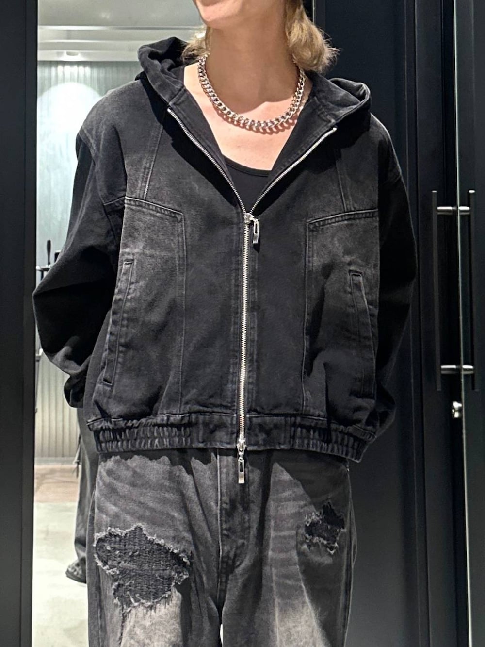 ブラック系のデニムパンツ、ブラック系のブルゾン、シルバー系のネックレスを着用したメンズの秋コーディネートの2枚目の写真