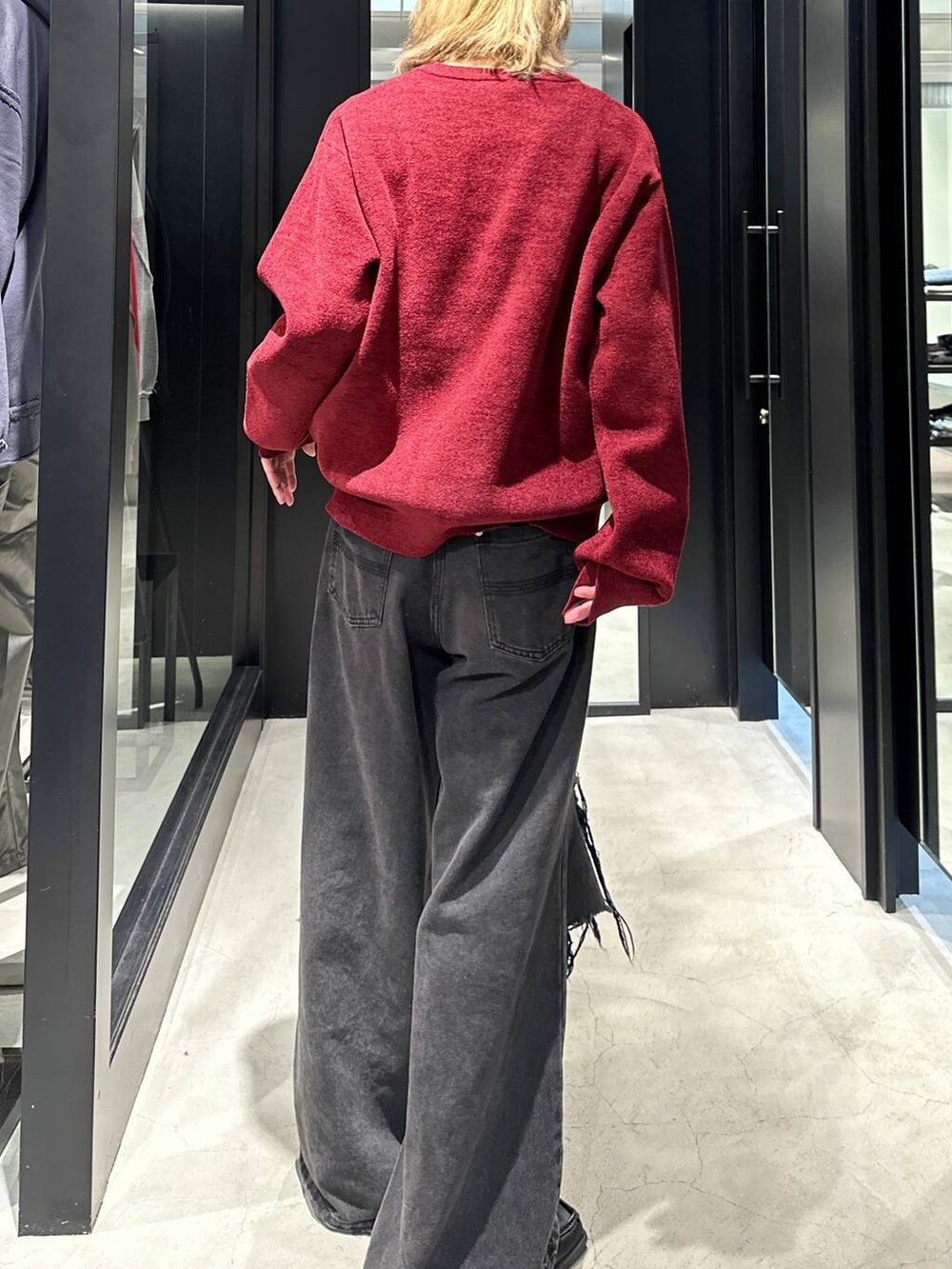 ブラック系のデニムパンツ、レッド系のニット/セーター、ブラック系のキャップを着用したメンズの秋コーディネートの4枚目の写真