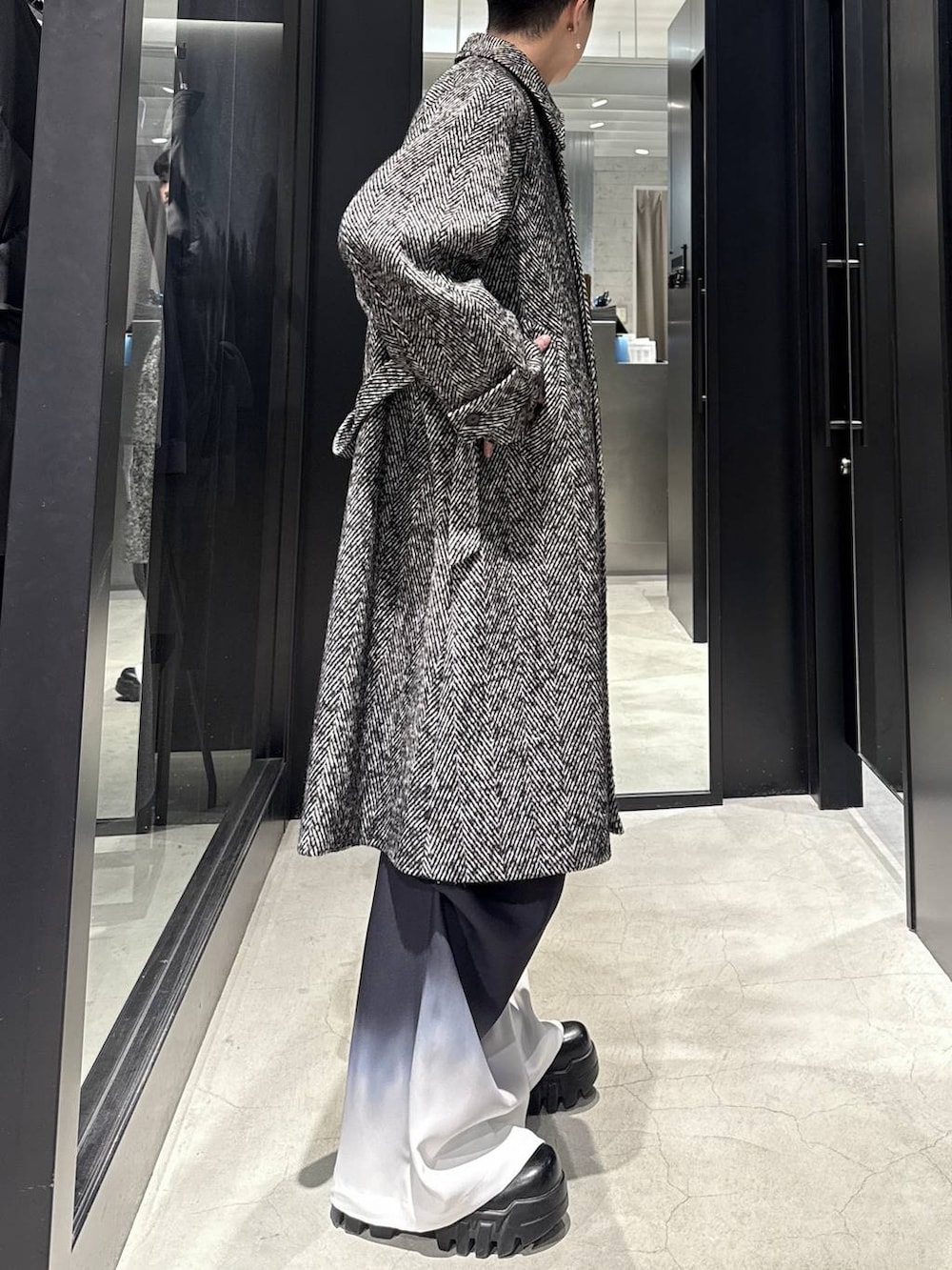 グレー系のステンカラーコート、ブラック系のその他パンツを着用したメンズの冬コーディネートの2枚目の写真