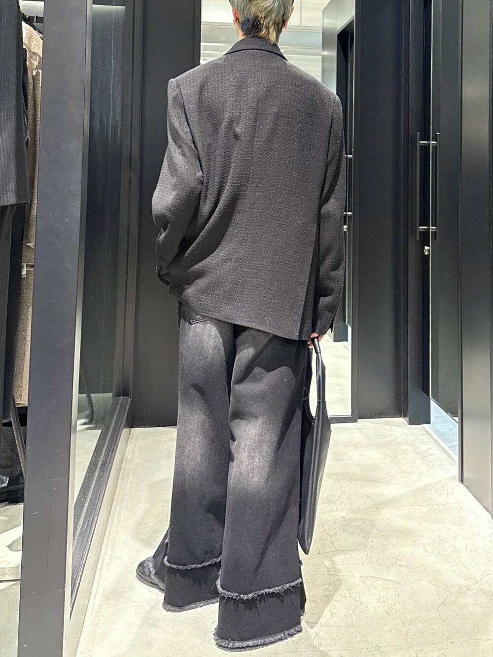 ブラック系のトートバッグ、ブラック系のテーラードジャケット、ブラック系のデニムパンツを着用したメンズの冬コーディネートの3枚目の写真