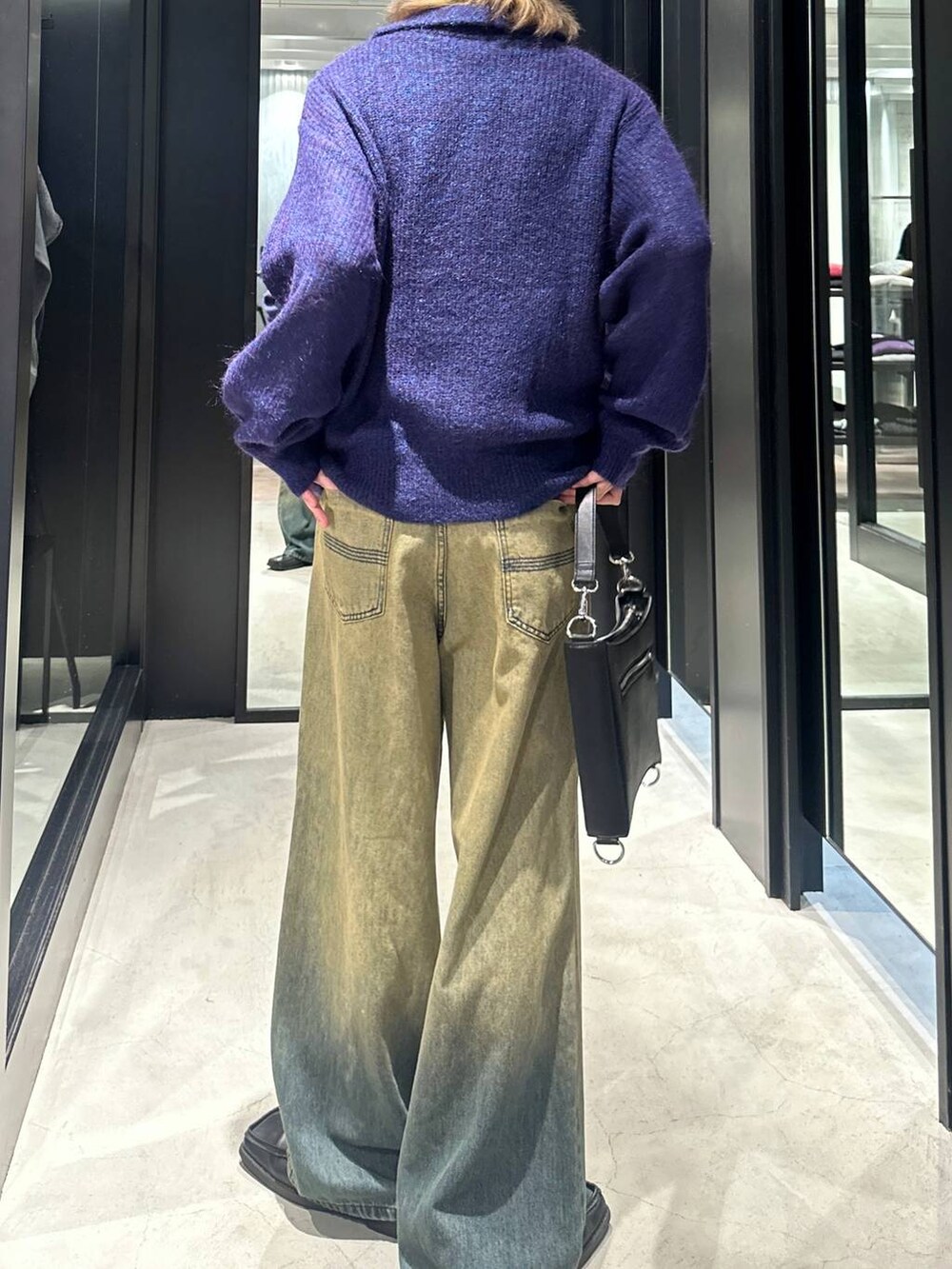 グリーン系のデニムパンツ、ブラック系のショルダーバッグ、ブルー系のニット/セーターを着用したメンズの秋コーディネートの4枚目の写真