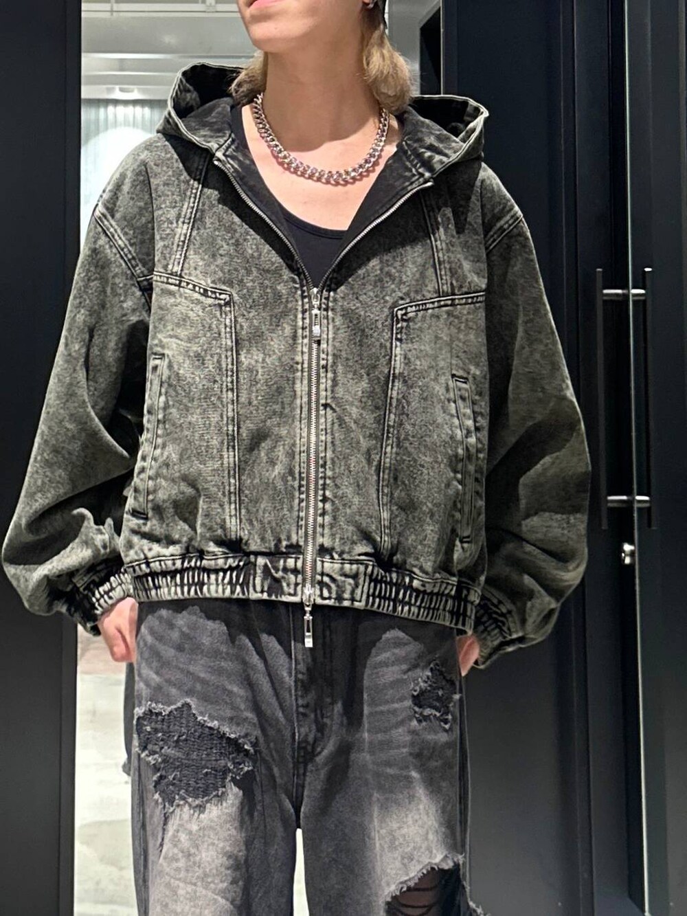ブラック系のデニムパンツ、グリーン系のブルゾン、シルバー系のネックレスを着用したメンズの秋コーディネートの2枚目の写真