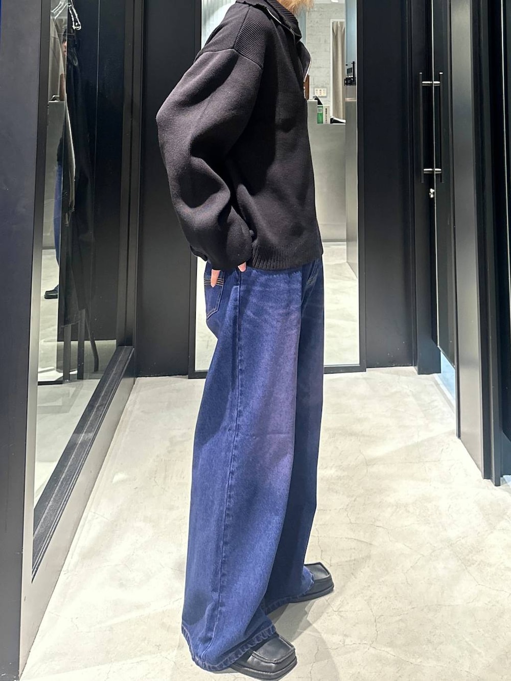 パープル系のデニムパンツ、ブラック系のニット/セーター、シルバー系のネックレスを着用したメンズの秋コーディネートの3枚目の写真