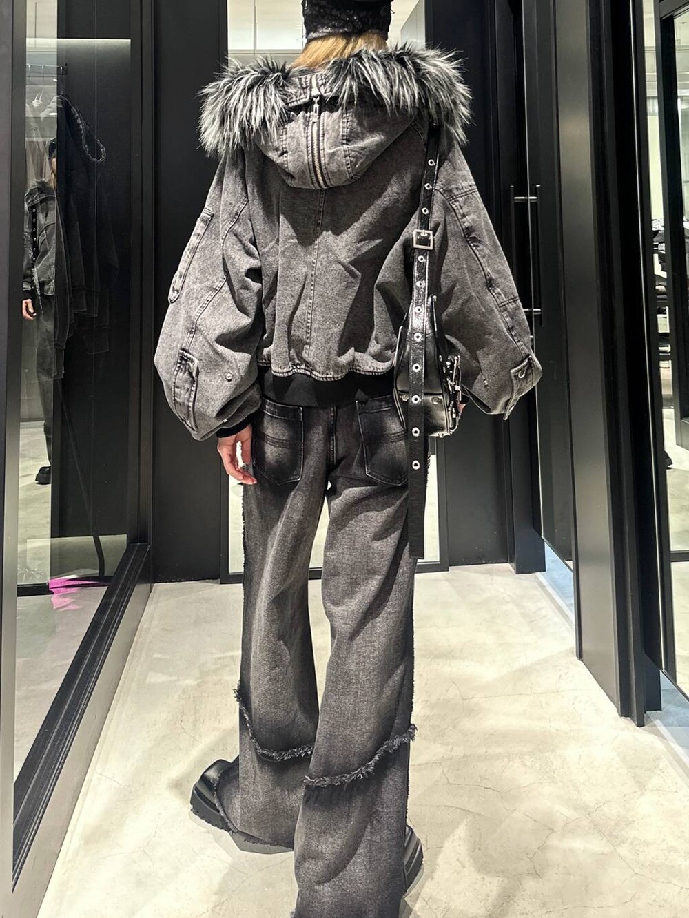 ブラック系のデニムパンツ、ブラック系のショルダーバッグ、グレー系のブルゾンを着用したメンズの秋コーディネートの4枚目の写真