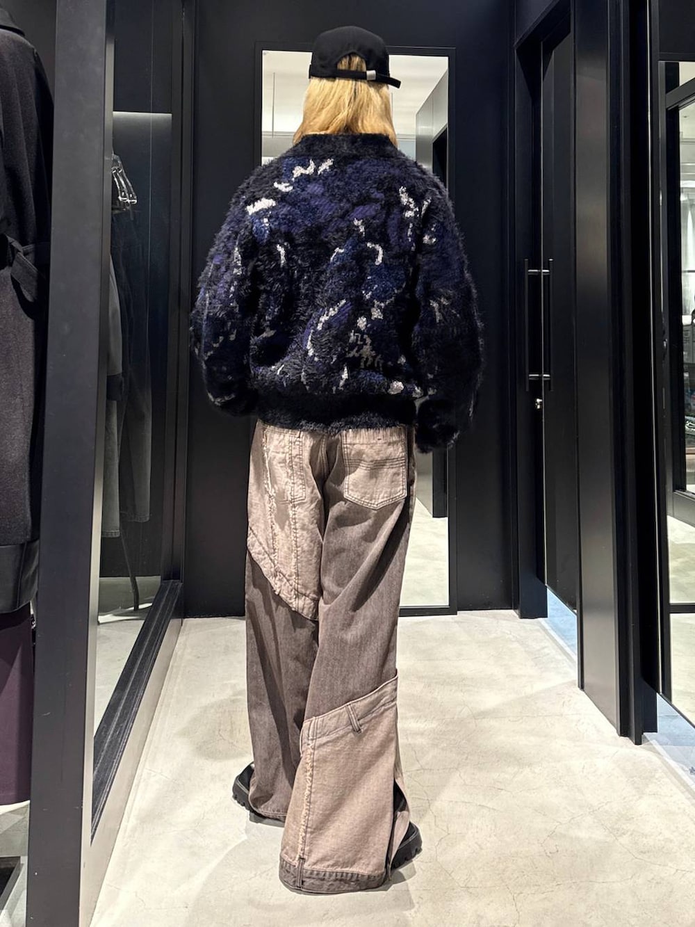 ブラウン系のデニムパンツ、ブラック系のニット/セーター、ブラック系のキャップを着用したメンズの秋コーディネートの2枚目の写真