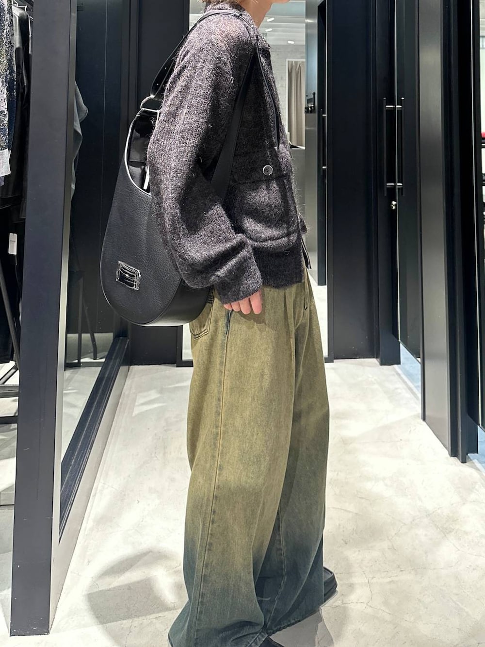グリーン系のデニムパンツ、ブラック系のニット/セーター、ブラック系のショルダーバッグを着用したメンズの秋コーディネートの3枚目の写真