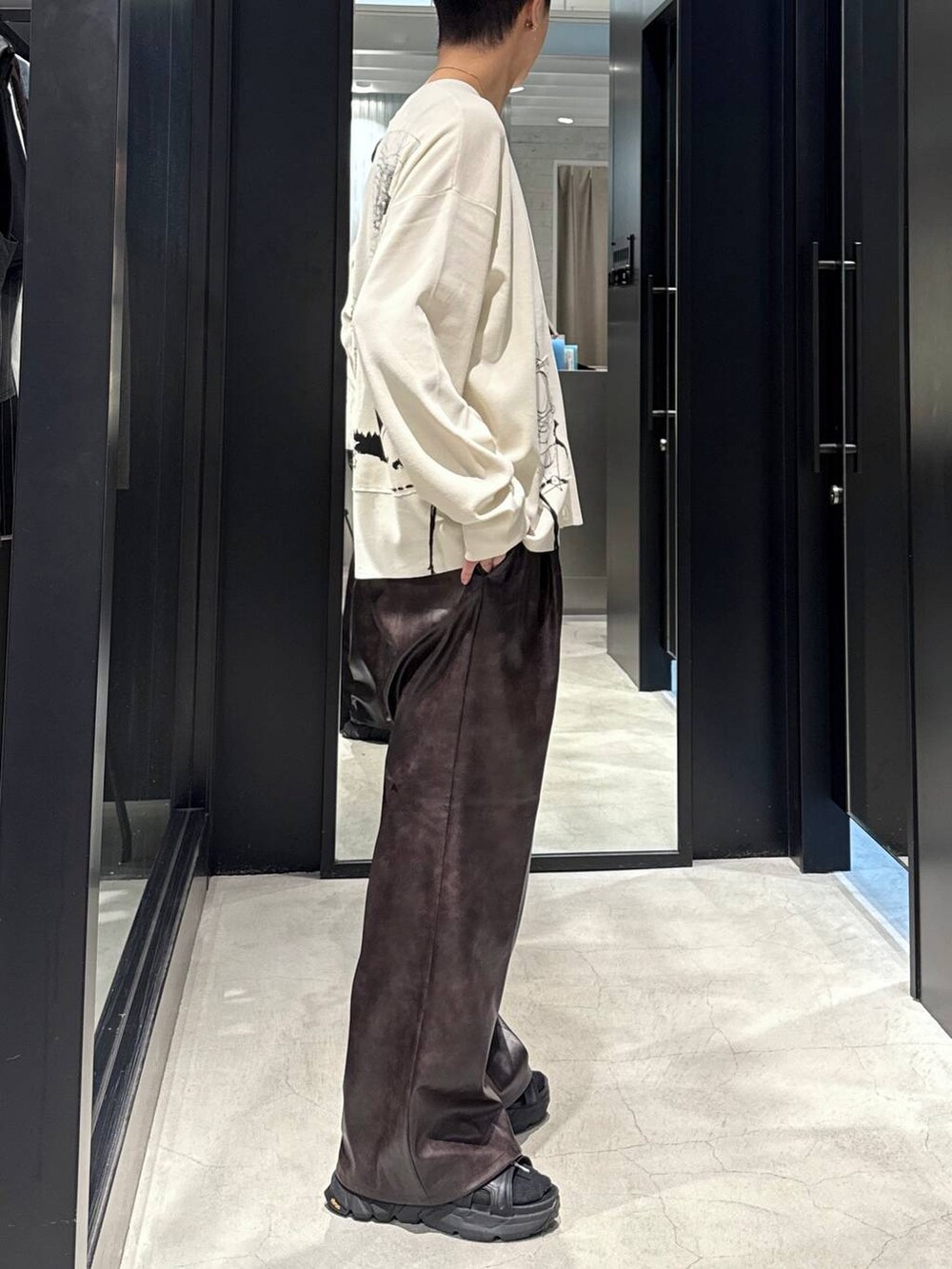 ブラック系のサンダル、ブラック系のタンクトップ、ブラウン系のスラックスを着用したメンズの夏コーディネートの2枚目の写真