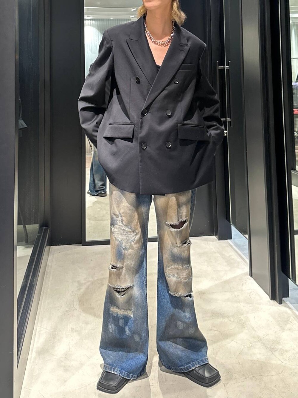ブラック系のテーラードジャケット、ブルー系のデニムパンツ、シルバー系のネックレスを着用したメンズの秋コーディネートの2枚目の写真