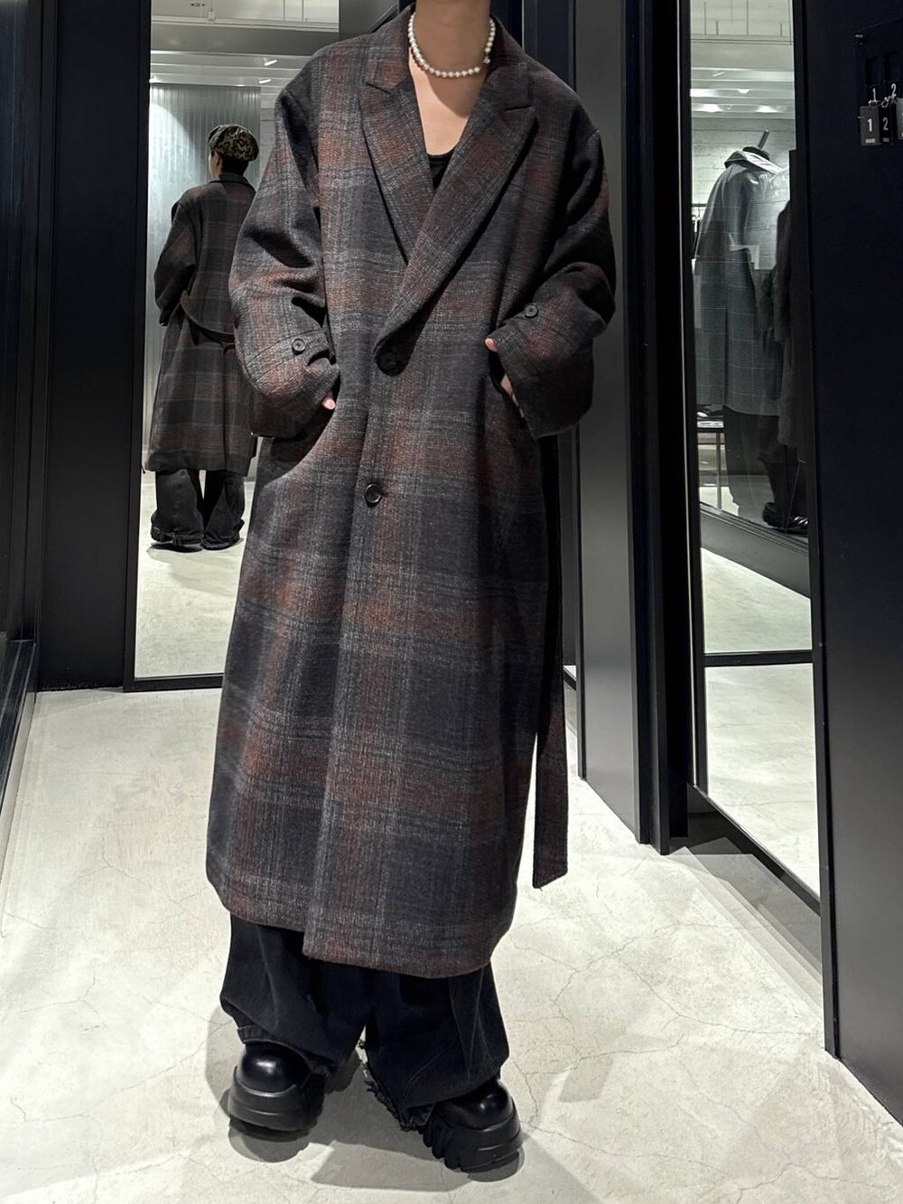 ブラック系のデニムパンツ、ブラック系のスウェット、グレー系のチェスターコートを着用したメンズの秋コーディネートの4枚目の写真