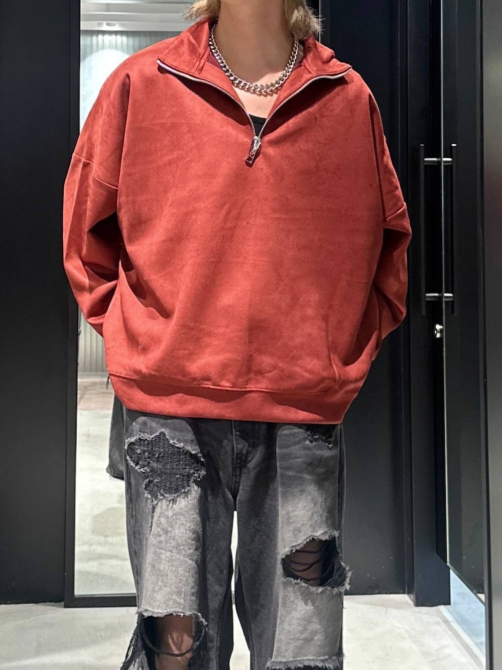 ブラック系のデニムパンツ、オレンジ系のスウェット、シルバー系のネックレスを着用したメンズの秋コーディネートの2枚目の写真