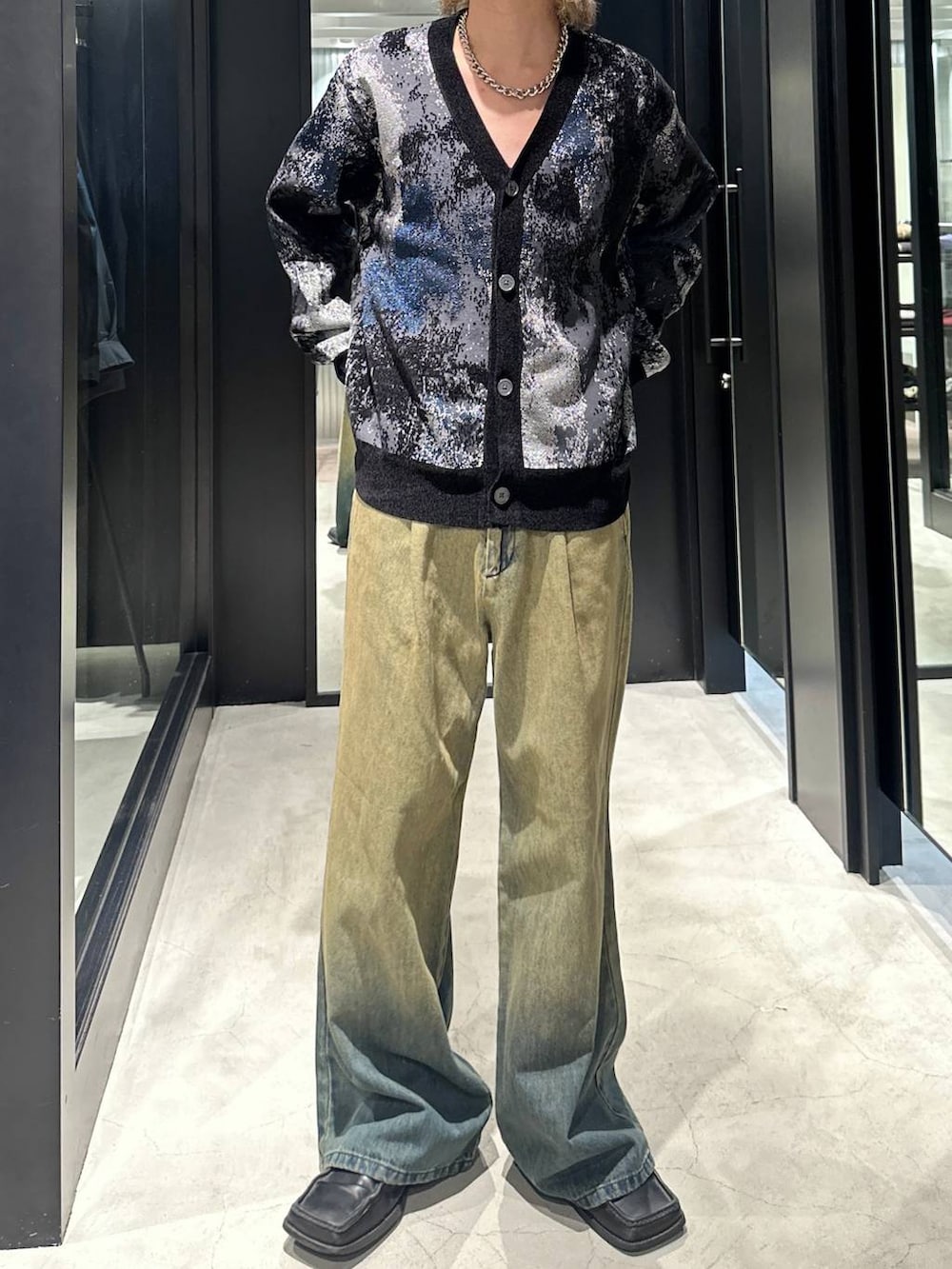 グリーン系のデニムパンツ、ブラック系のカーディガン/ボレロ、シルバー系のネックレスを着用したメンズの秋コーディネートの2枚目の写真