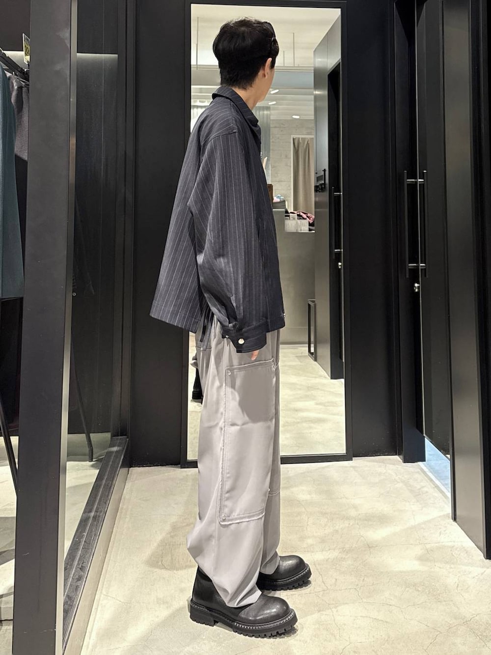 ブルー系のブルゾン、ブラック系のブーツ、シルバー系のネックレスを着用したメンズの秋コーディネートの2枚目の写真