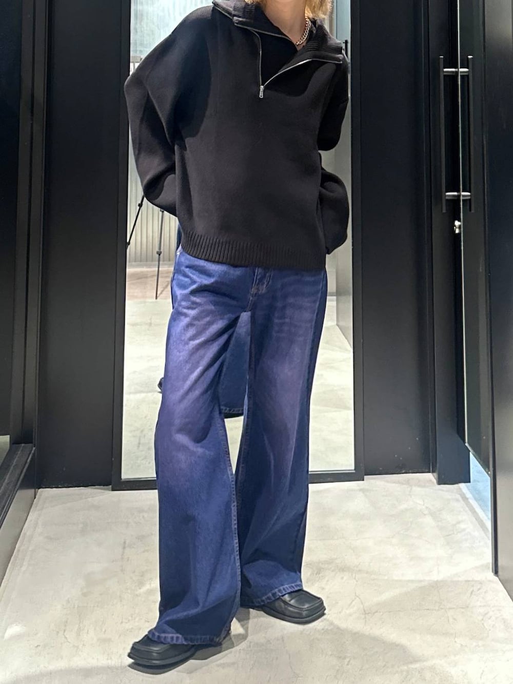 パープル系のデニムパンツ、ブラック系のニット/セーター、シルバー系のネックレスを着用したメンズの秋コーディネートの2枚目の写真