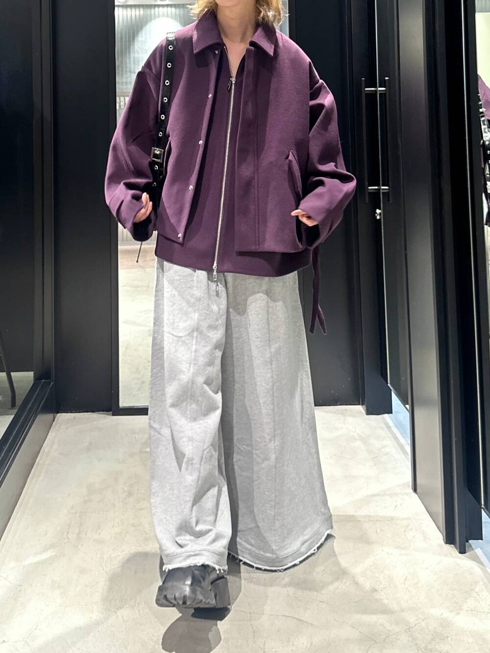 グレー系のスウェットパンツ、ブラック系のショルダーバッグ、パープル系のブルゾンを着用したメンズの秋コーディネートの3枚目の写真