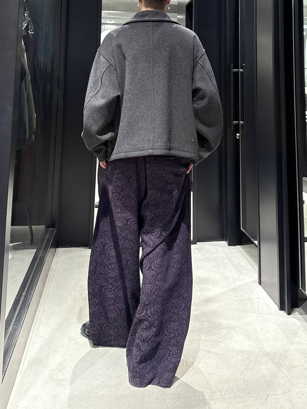 グレー系のブルゾン、パープル系のスラックスを着用したメンズの秋コーディネートの3枚目の写真