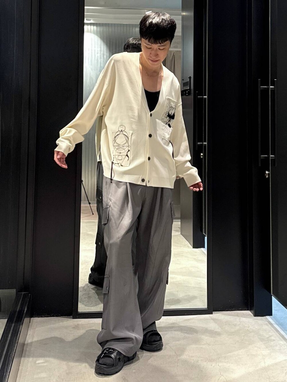 ブラック系のサンダル、ブラック系のタンクトップ、グレー系のカーゴパンツを着用したメンズの夏コーディネートの4枚目の写真