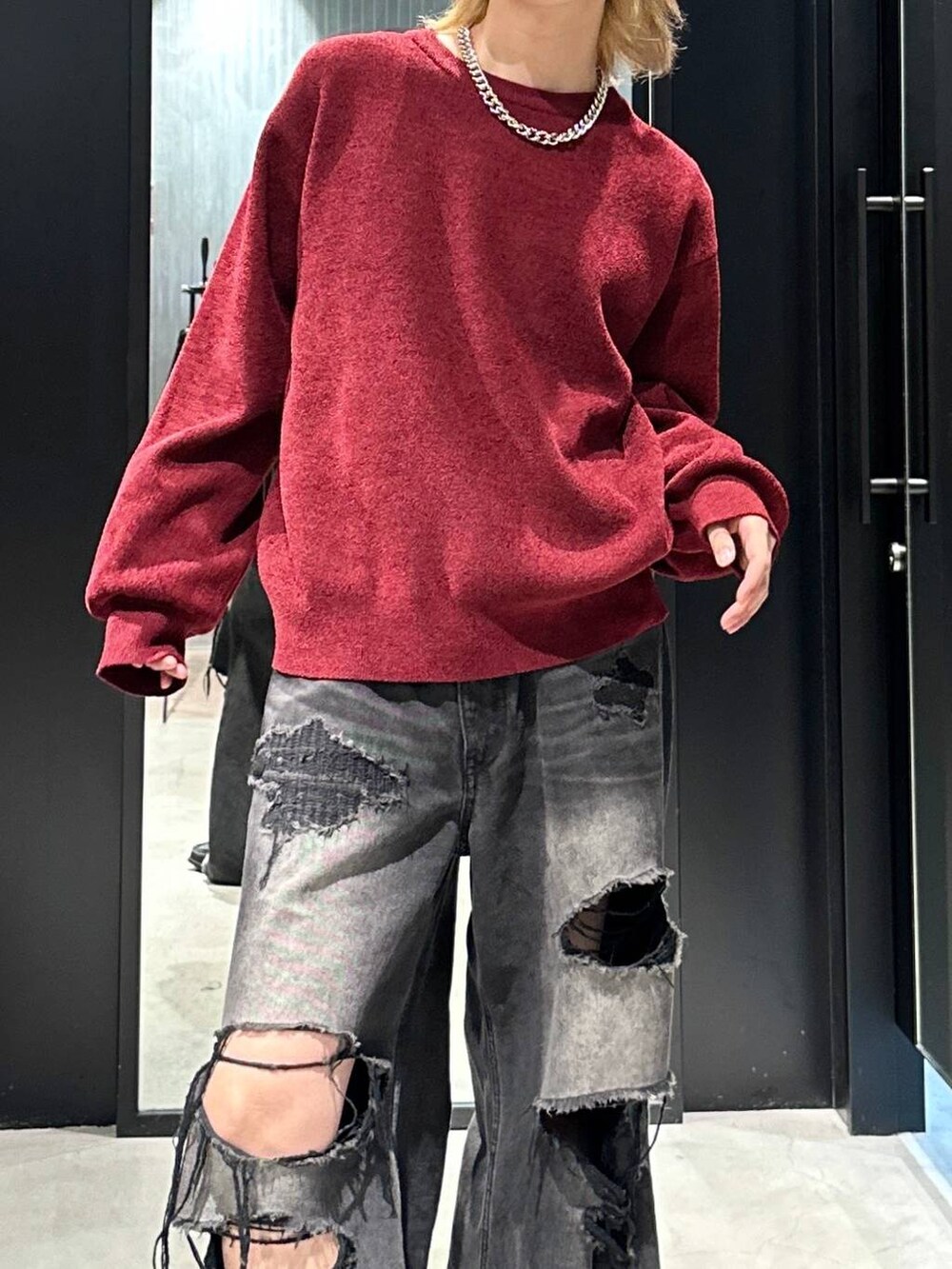 ブラック系のデニムパンツ、レッド系のニット/セーター、ブラック系のキャップを着用したメンズの秋コーディネートの2枚目の写真