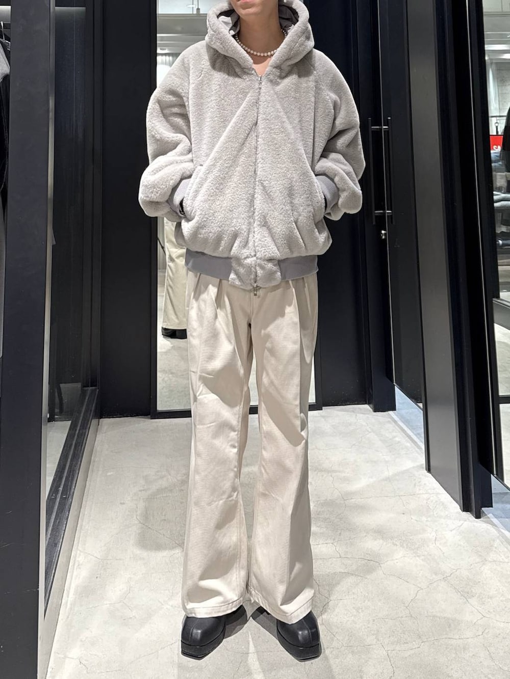 グレー系のブルゾン、ブラック系のブーツ、ホワイト系のデニムパンツを着用したメンズの冬コーディネートの4枚目の写真