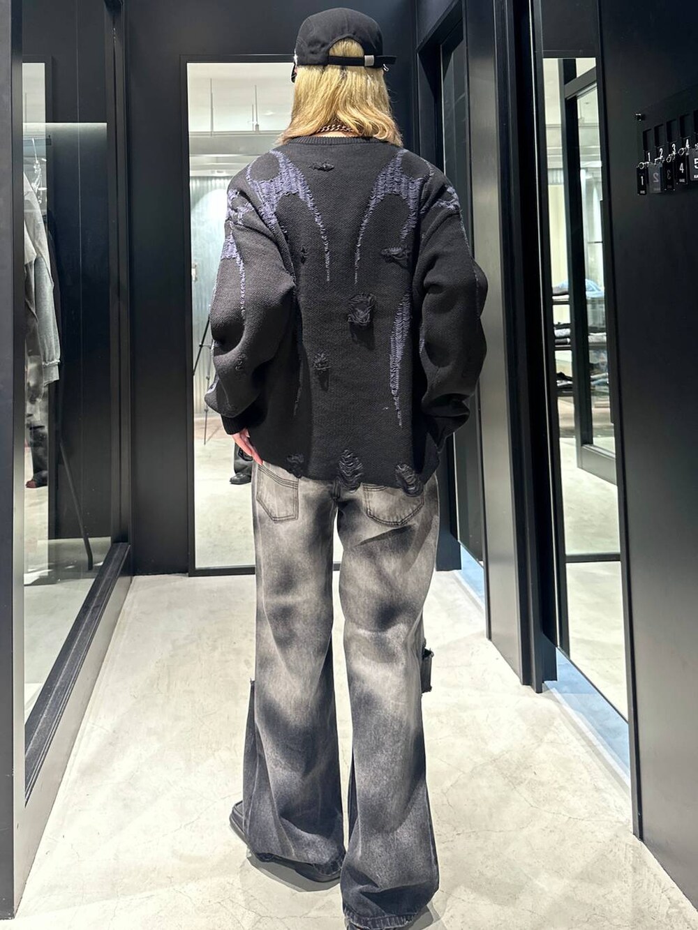 ブラック系のデニムパンツ、ブラック系のニット/セーター、ブラック系のキャップを着用したメンズの秋コーディネートの4枚目の写真