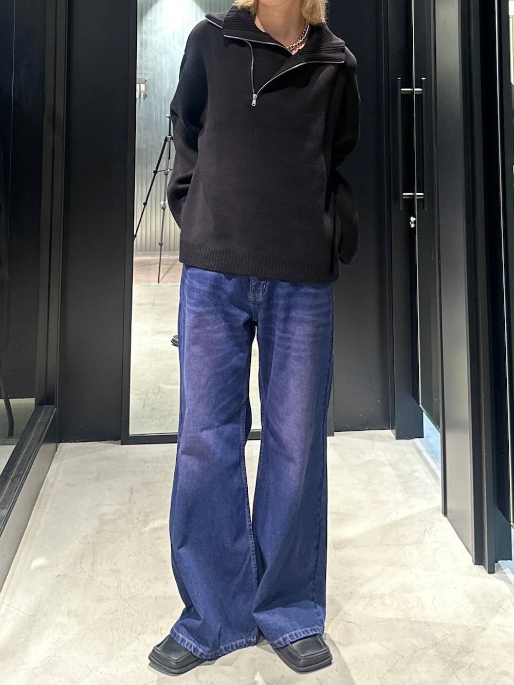 パープル系のデニムパンツ、ブラック系のニット/セーター、シルバー系のネックレスを着用したメンズの秋コーディネートの4枚目の写真