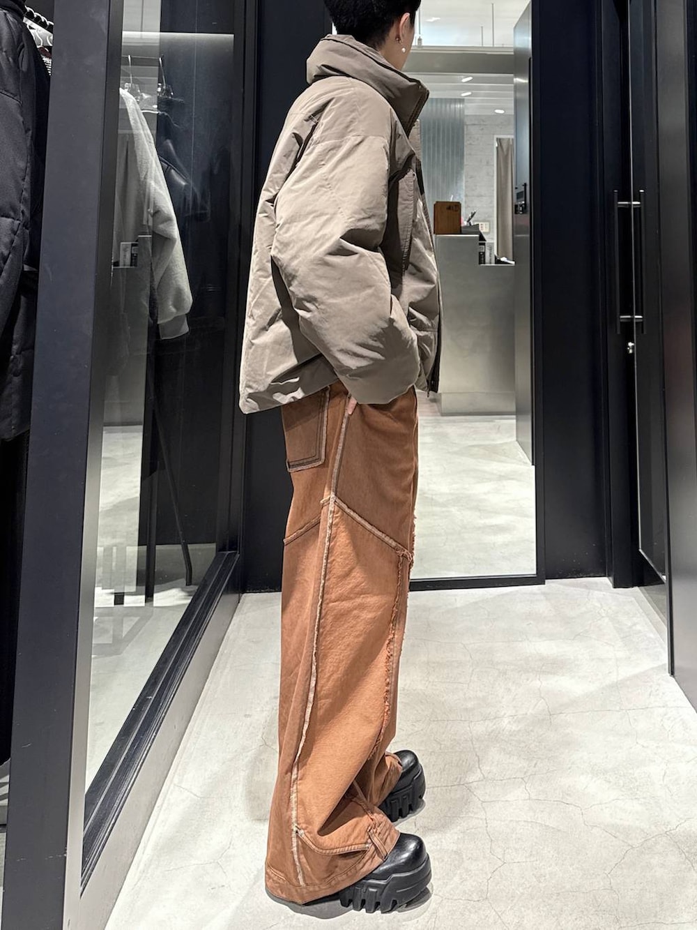 ブラウン系のダウンジャケット/コート、オレンジ系のデニムパンツ、シルバー系のネックレスを着用したメンズの冬コーディネートの2枚目の写真