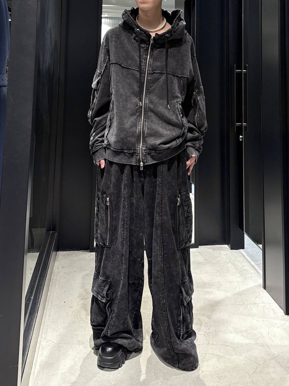 ブラック系のスウェットパンツ、ブラック系のパーカー、ホワイト系のネックレスを着用したメンズの冬コーディネートの4枚目の写真