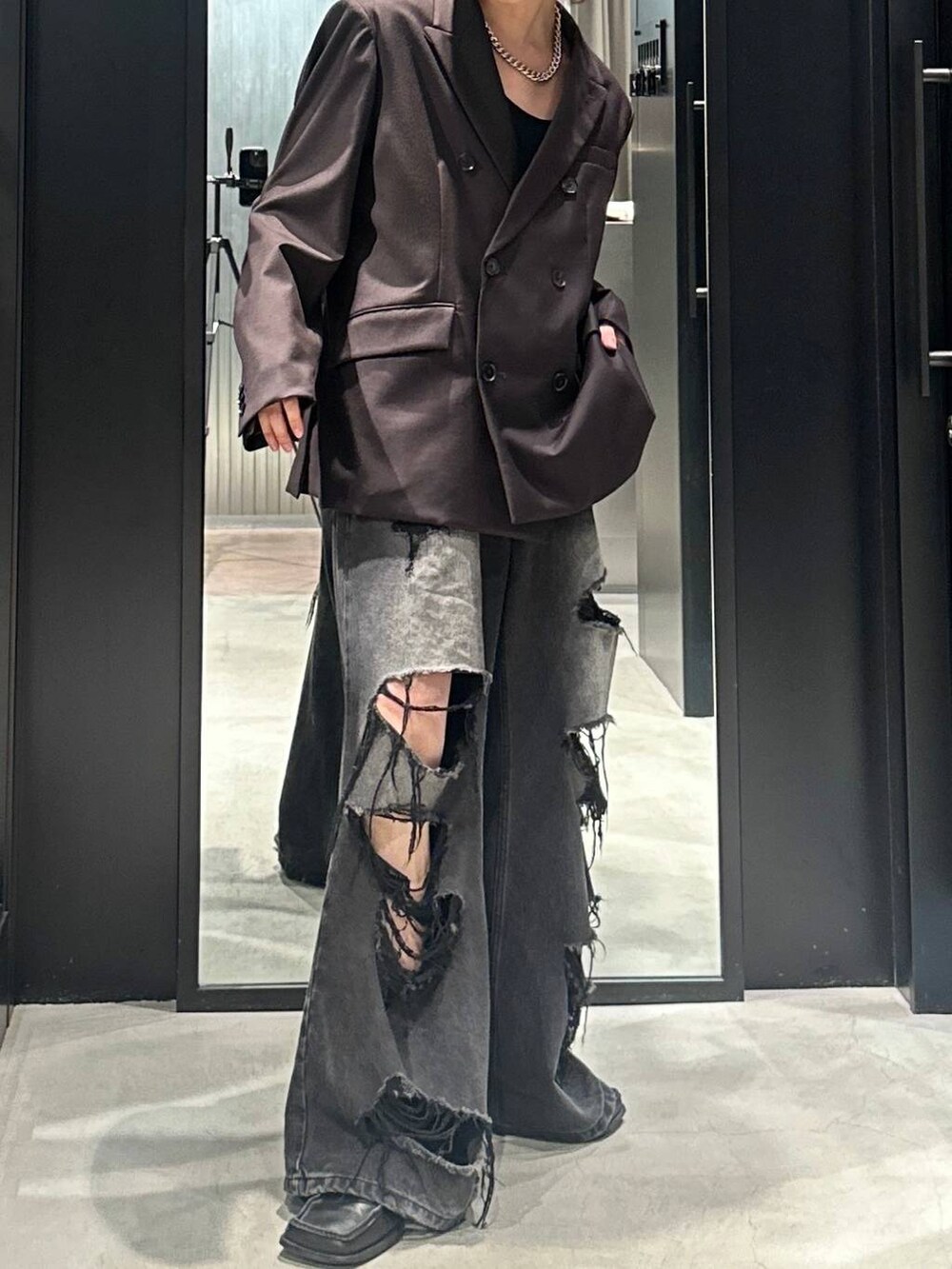ブラック系のデニムパンツ、ブラウン系のテーラードジャケット、シルバー系のネックレスを着用したメンズの秋コーディネートの2枚目の写真