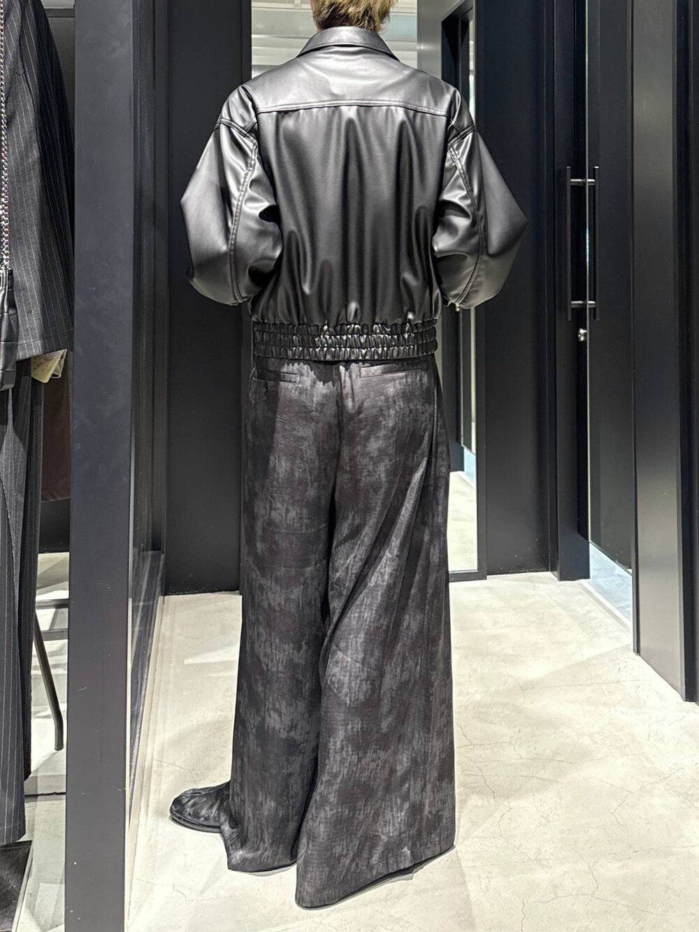 グレー系のスラックス、ブラック系のキャップ、シルバー系のネックレスを着用したメンズの冬コーディネートの3枚目の写真