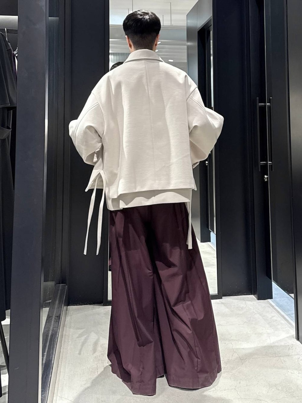 ホワイト系のブルゾン、ブラック系のブーツ、レッド系のその他パンツを着用したメンズの秋コーディネートの3枚目の写真