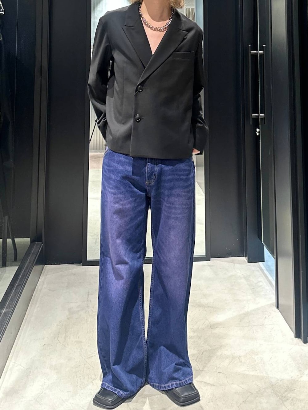パープル系のデニムパンツ、ブラック系のテーラードジャケット、シルバー系のネックレスを着用したメンズの秋コーディネートの3枚目の写真