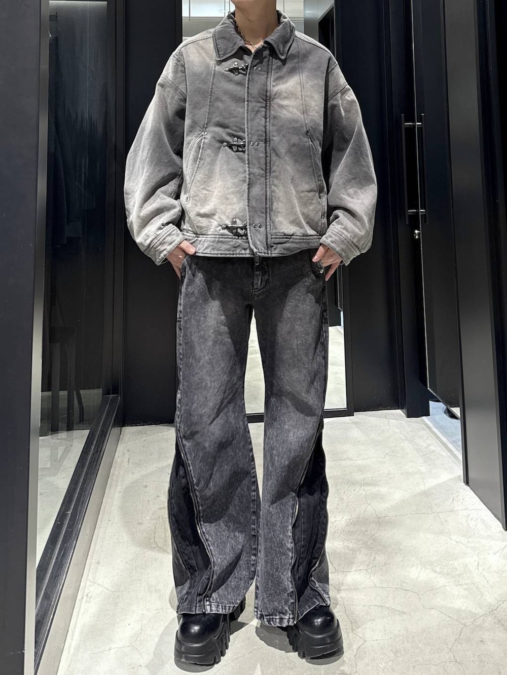 ブラック系のデニムパンツ、グレー系のブルゾン、シルバー系のネックレスを着用したメンズの冬コーディネートの4枚目の写真