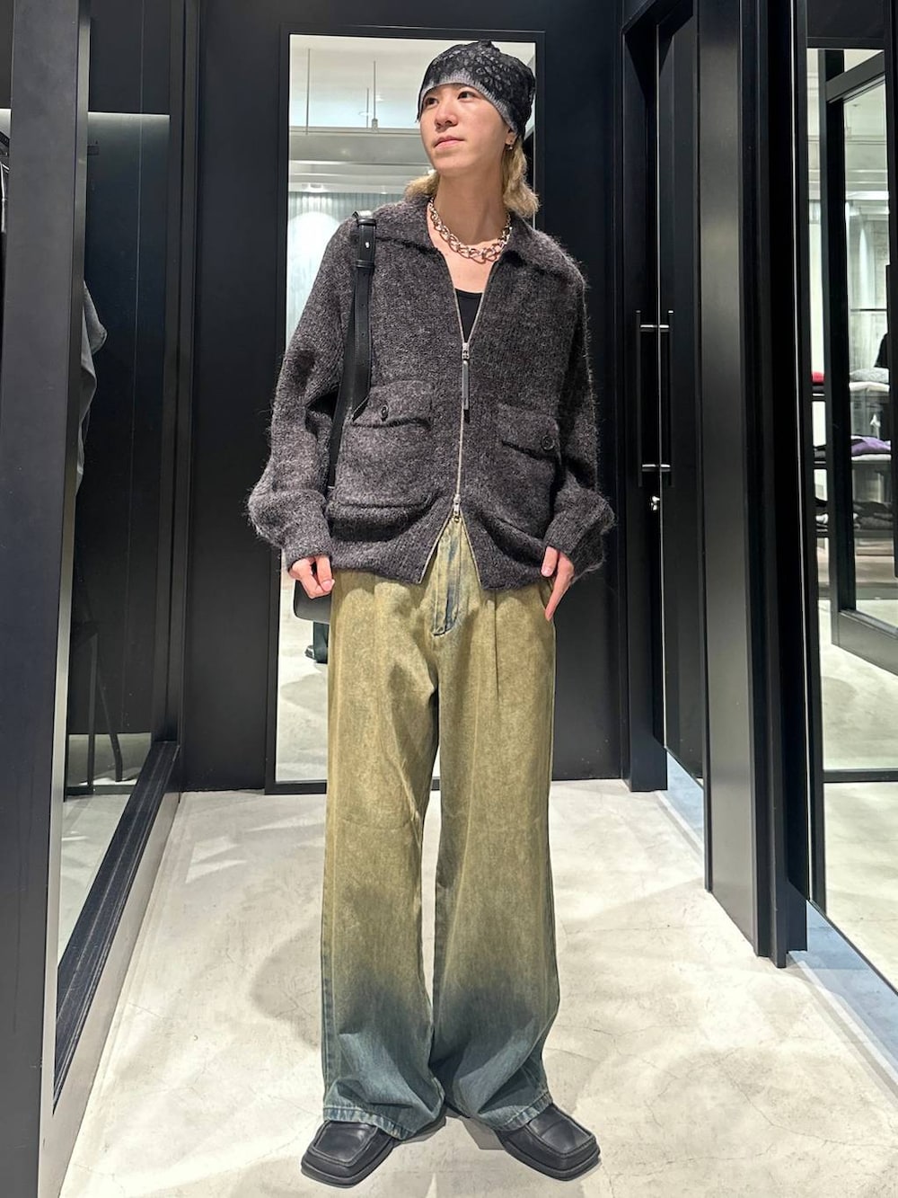グリーン系のデニムパンツ、ブラック系のニット/セーター、ブラック系のショルダーバッグを着用したメンズの秋コーディネートの5枚目の写真