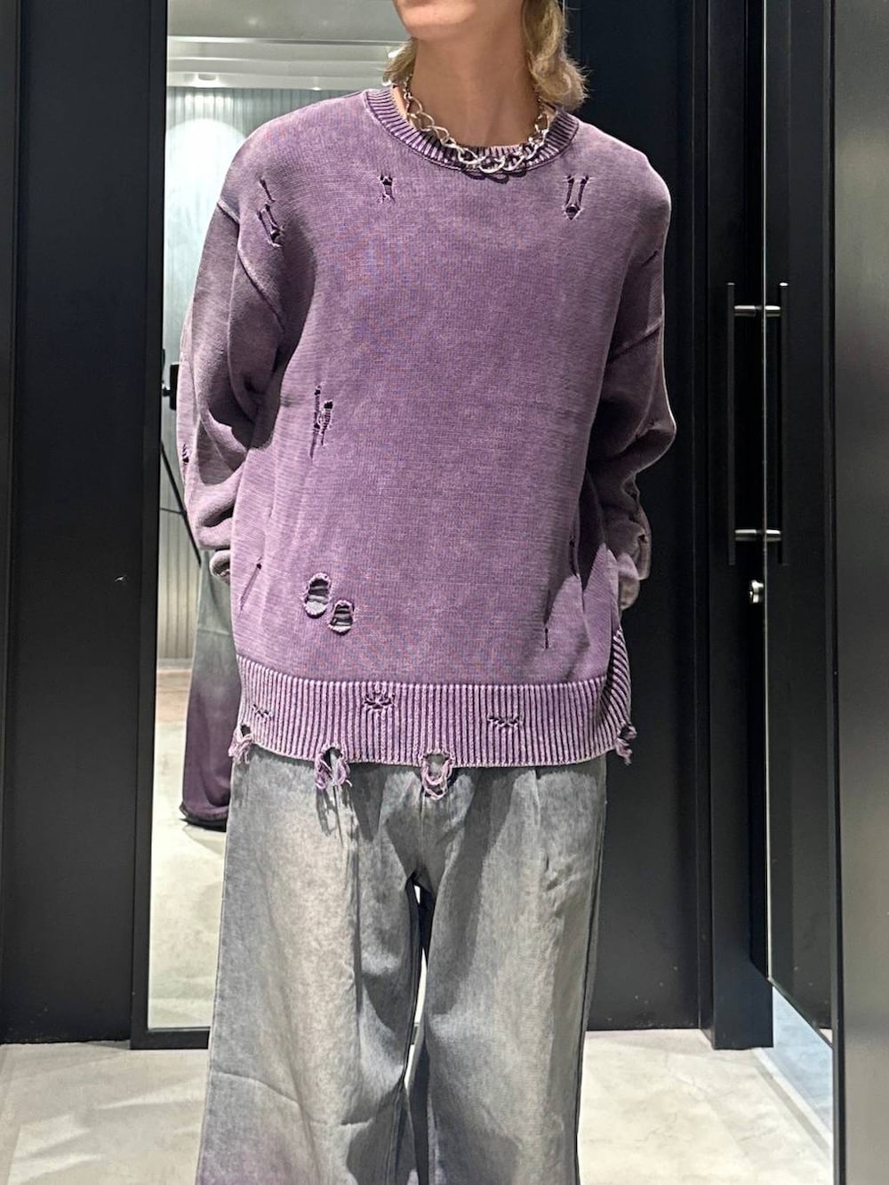 パープル系のデニムパンツ、パープル系のニット/セーター、シルバー系のネックレスを着用したメンズの秋コーディネートの3枚目の写真