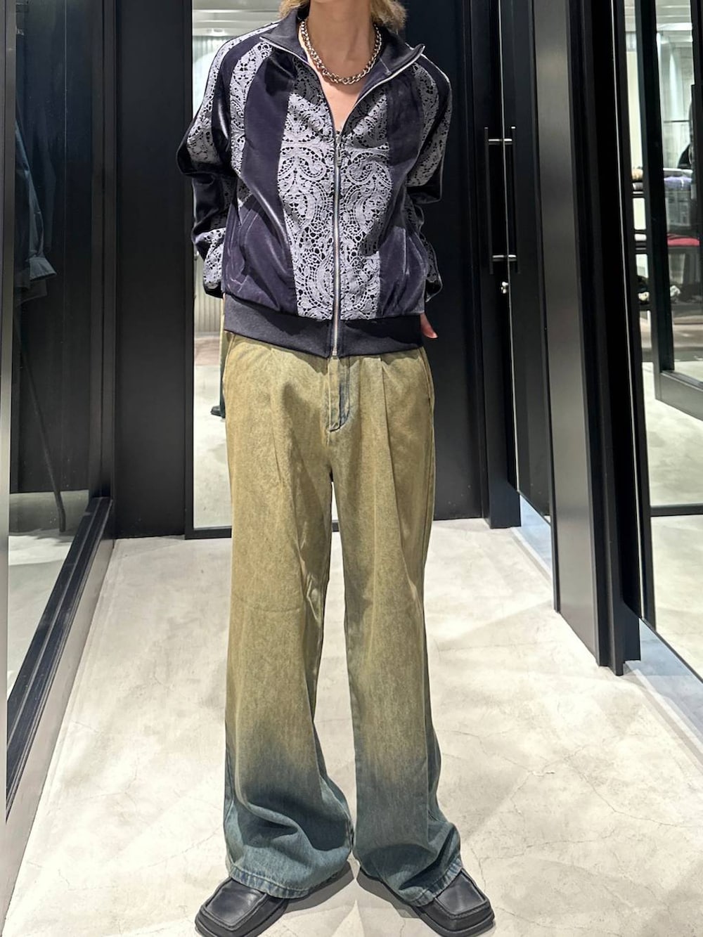 グリーン系のデニムパンツ、グレー系のブルゾン、シルバー系のネックレスを着用したメンズの秋コーディネートの2枚目の写真