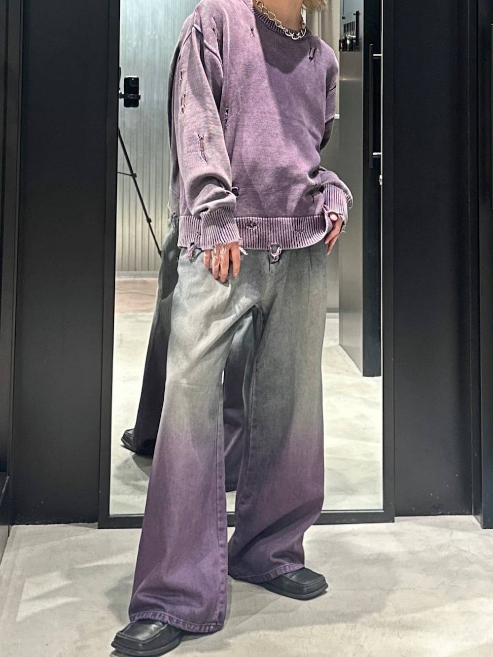 パープル系のデニムパンツ、パープル系のニット/セーター、シルバー系のネックレスを着用したメンズの秋コーディネートの2枚目の写真