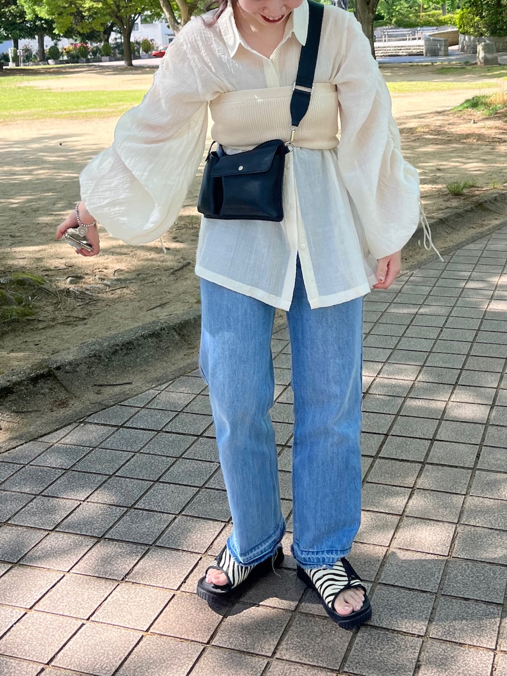 ホワイト系のシャツ/ブラウス、ブルー系のデニムパンツ、ブラック系のボディバッグ/ウエストポーチを着用したレディースの春コーディネートの2枚目の写真