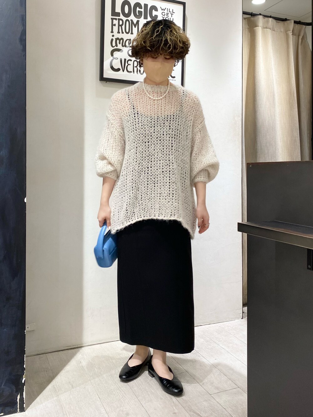 ホワイト系のニット/セーター、ブラック系のワンピース、ブルー系のハンドバッグを着用したレディースの冬コーディネートの2枚目の写真