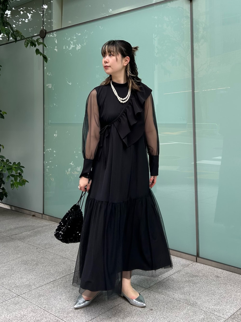 ブラック系のハンドバッグ、シルバー系のパンプス、ブラック系のワンピースを着用したレディースの冬コーディネートの2枚目の写真