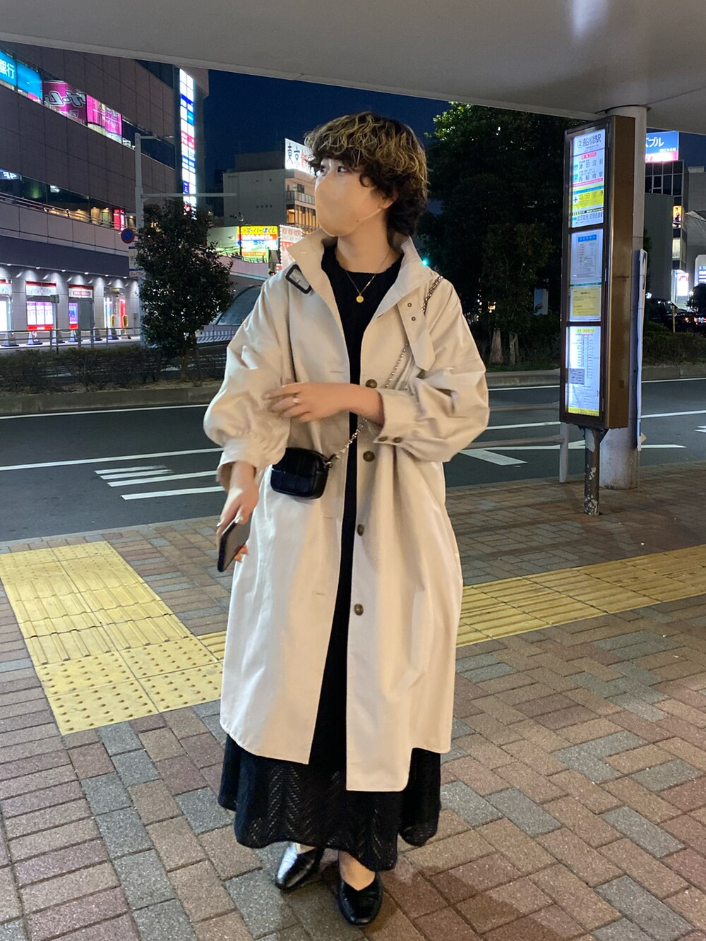 ホワイト系のトレンチコート、ブラック系のワンピース、ホワイト系のショルダーバッグを着用したレディースの冬コーディネートの2枚目の写真