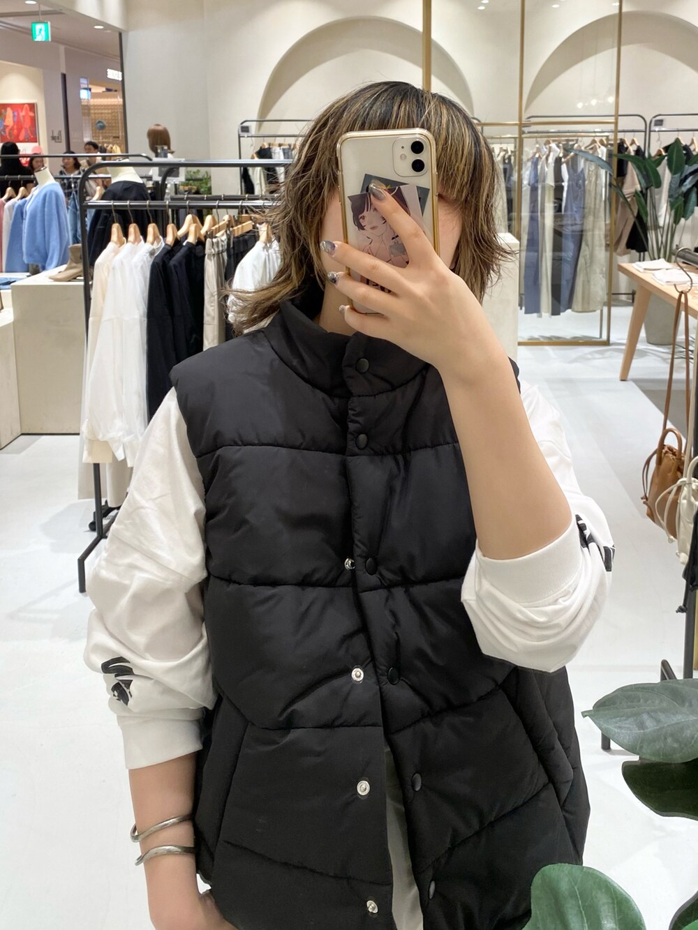 ブラック系のダウンベスト、ホワイト系のカーゴパンツを着用したレディースの秋コーディネートの2枚目の写真