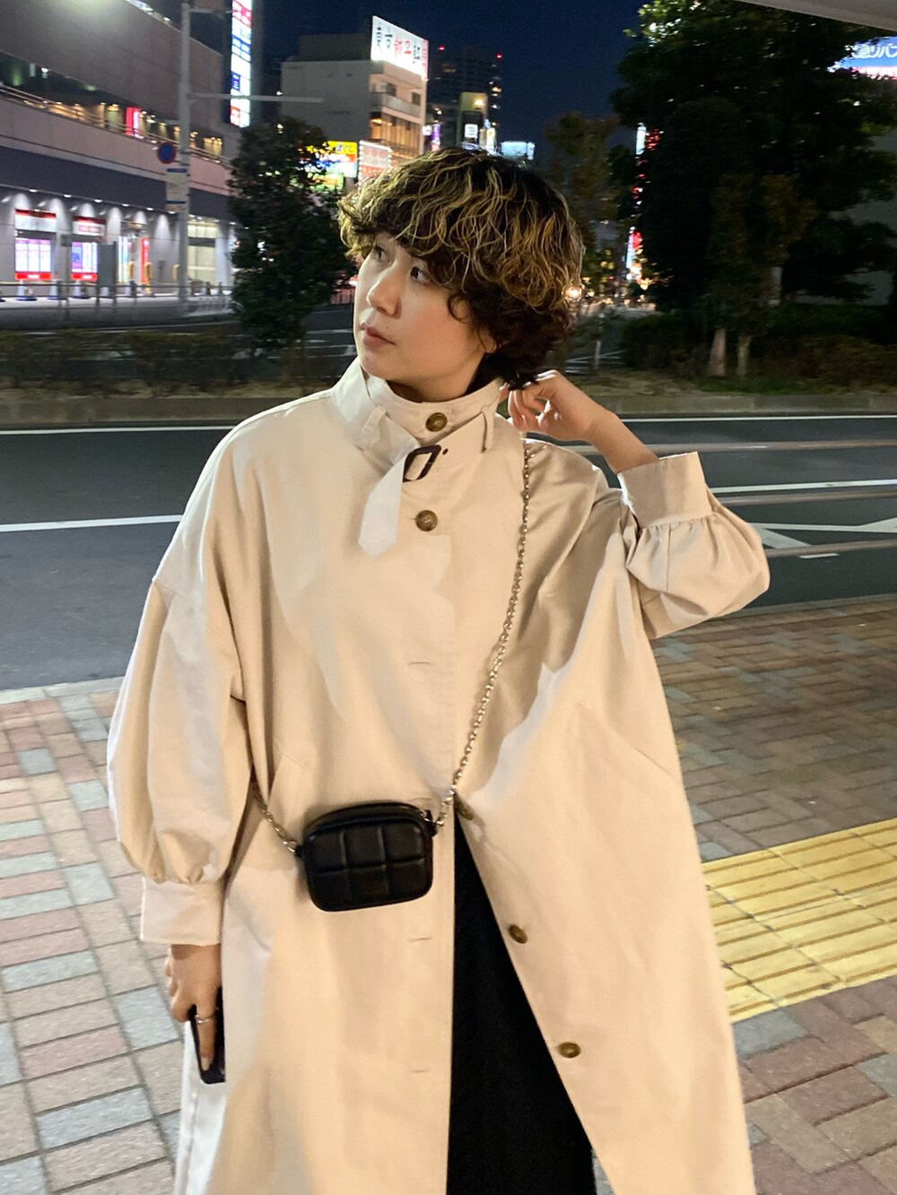 ホワイト系のトレンチコート、ブラック系のワンピース、ホワイト系のショルダーバッグを着用したレディースの冬コーディネートの3枚目の写真