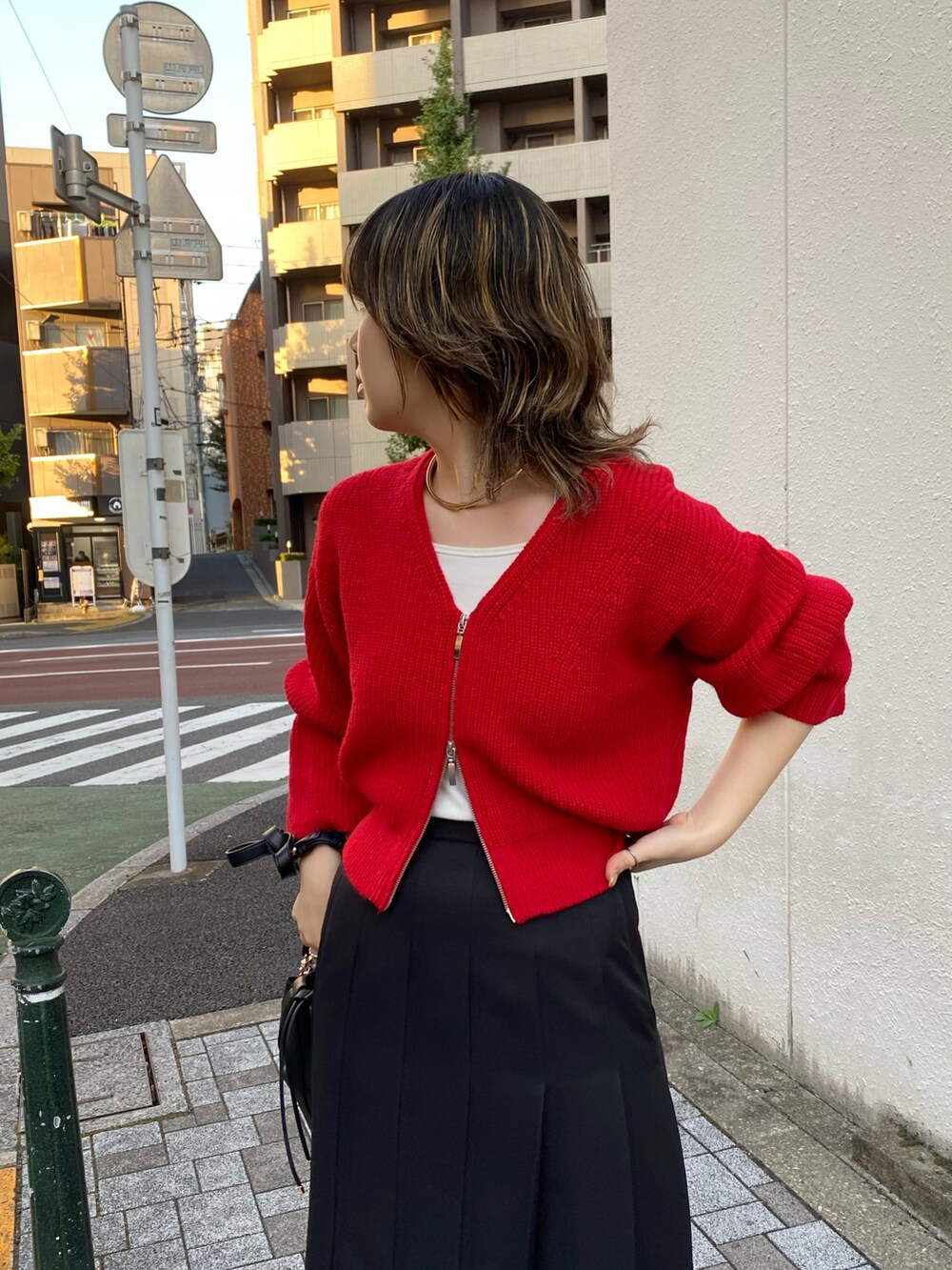 レッド系のニット/セーター、ブラック系のスカートを着用したレディースの秋コーディネートの2枚目の写真