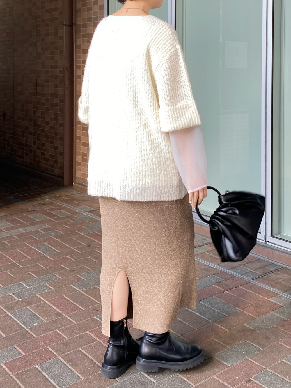 ベージュ系のスカート、ホワイト系のTシャツ/カットソー、ブラック系のハンドバッグを着用したレディースの冬コーディネートの2枚目の写真