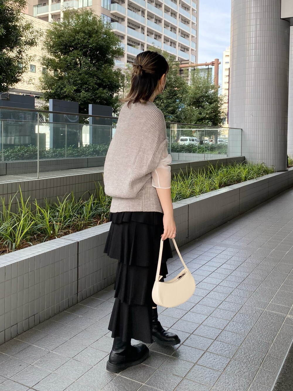 グレー系のベスト、ホワイト系のTシャツ/カットソー、ブラック系のスカートを着用したレディースの秋コーディネートの2枚目の写真