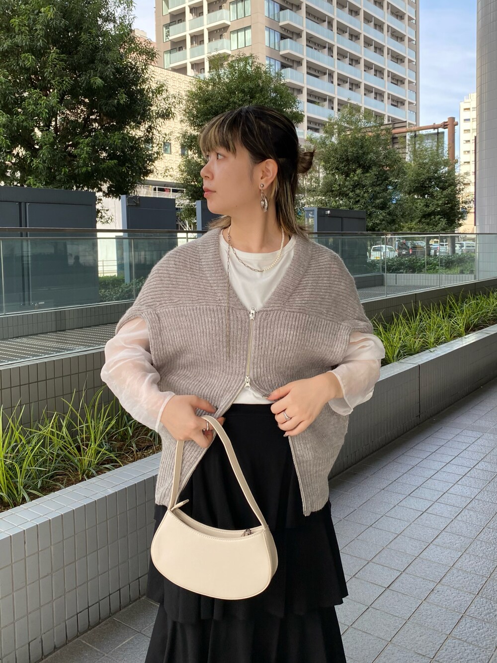 グレー系のベスト、ホワイト系のTシャツ/カットソー、ブラック系のスカートを着用したレディースの秋コーディネートの3枚目の写真